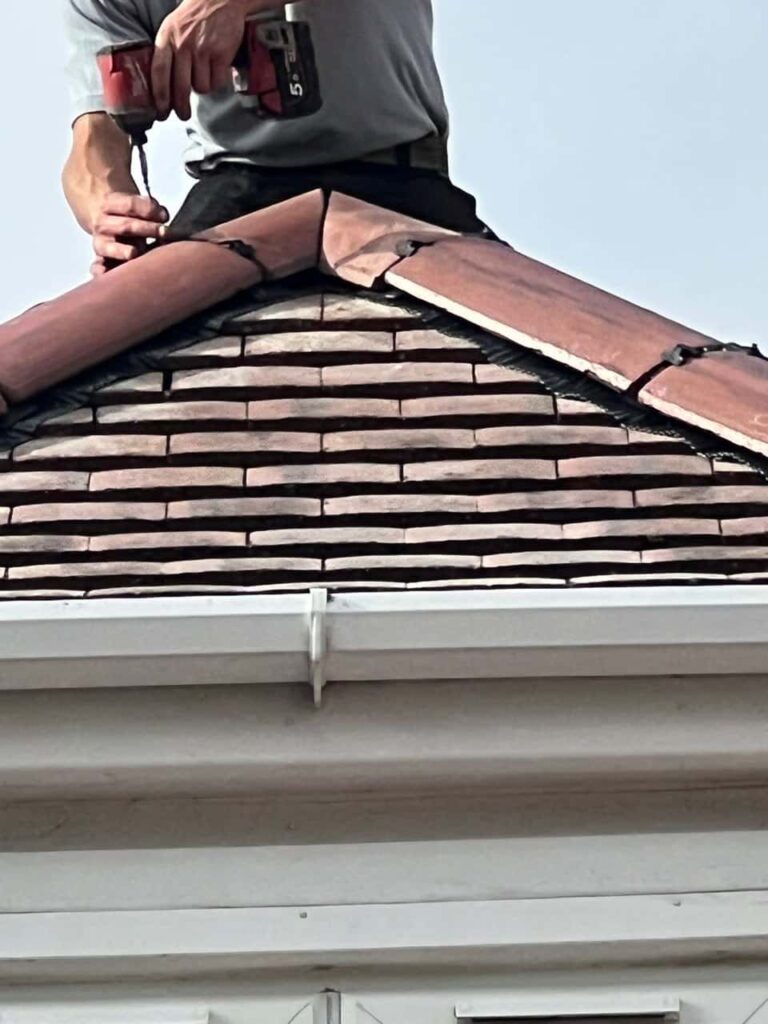 This is a photo of one of the operatives of Matlock Roofing Repairs installing new ridge tiles