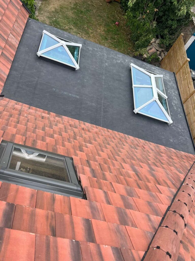 This is a photo taken from the roof ridge looking down a tiled pitched roof on to a flat roof. Works carried out by Matlock Roofing Repairs